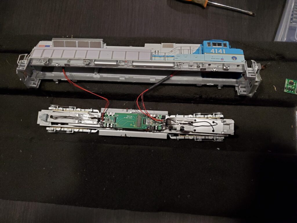 Model train disassembled on a black surface.